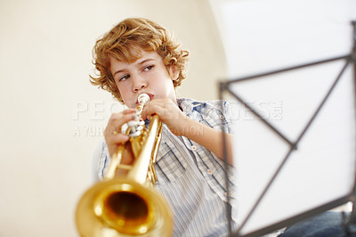 Buy stock photo Playing, music and child with notes and trumpet for practice, jazz lesson and learning for talent show. Musician, creative hobby and young boy with instrument, sheet and paper on song melody at home