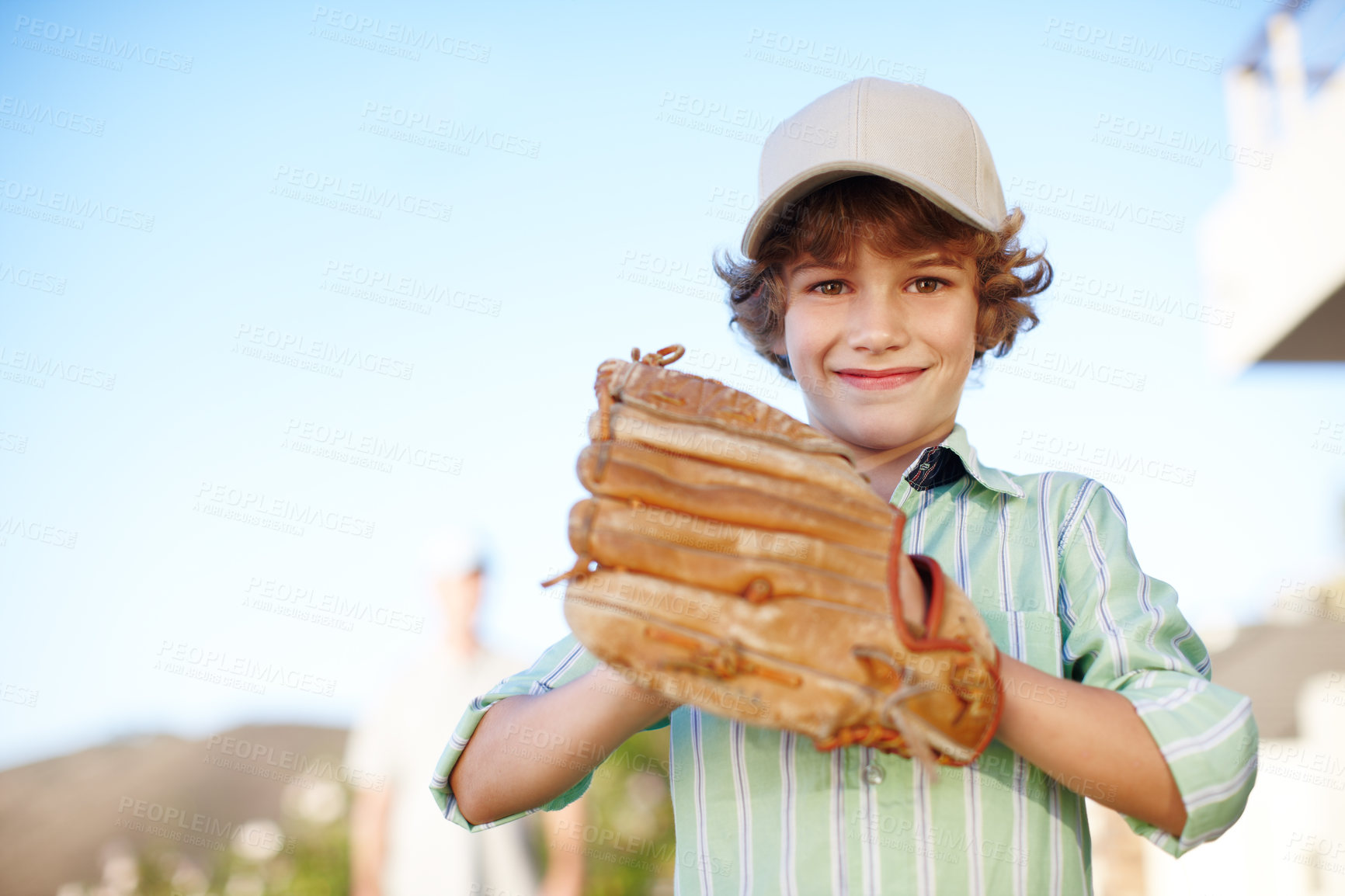 Buy stock photo Cropped portrait of a young boy playing baseball in the yard with his father in the background