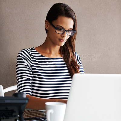 Buy stock photo Shot of an attractive young businesswoman working on a laptop at her desk