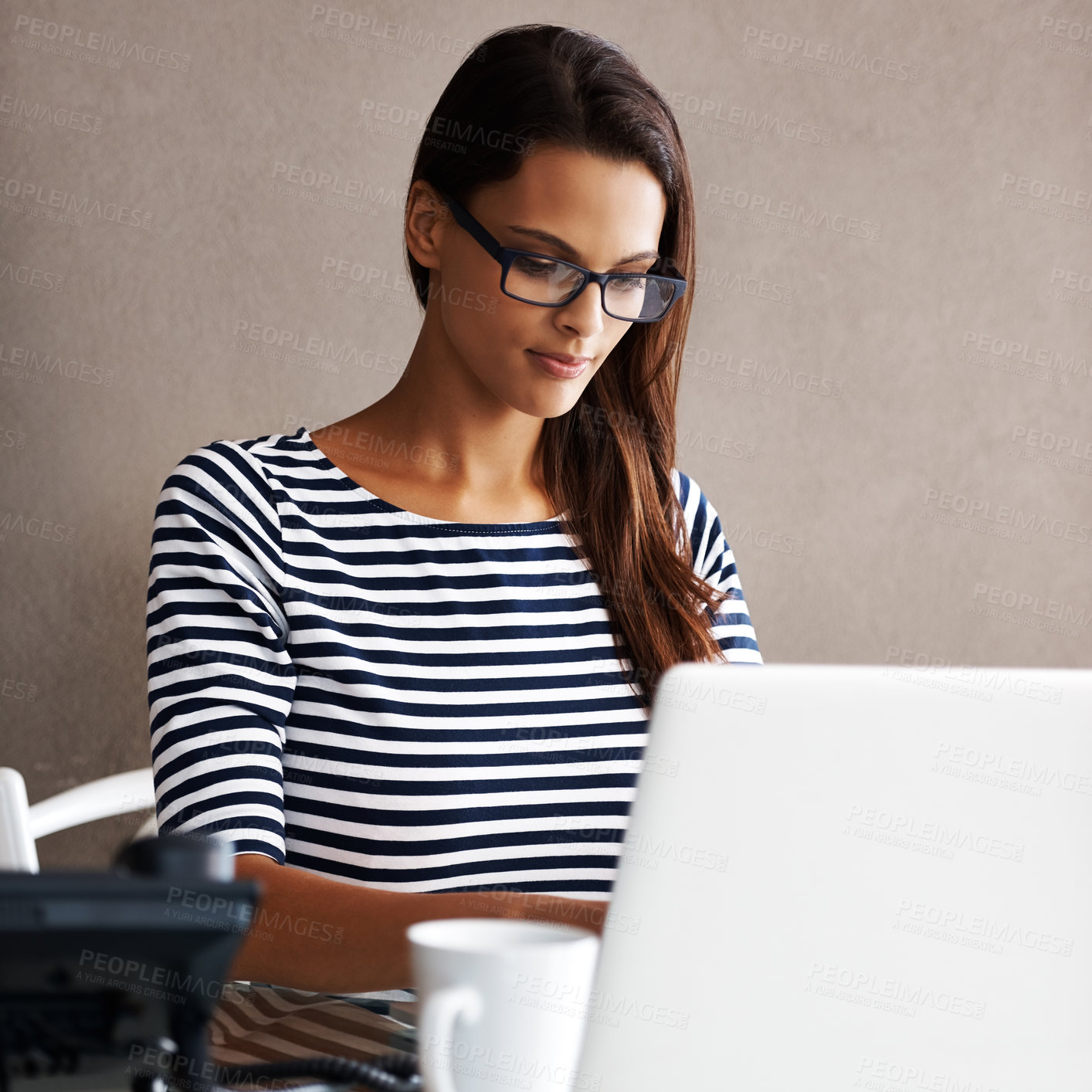 Buy stock photo Shot of an attractive young businesswoman working on a laptop at her desk