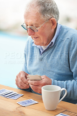 Buy stock photo Elderly man, coffee and playing cards on table for poker, relax and happy in retirement. Senior person, grandfather and beverage with thinking, hobby and fun strategy on patio in home drinking tea