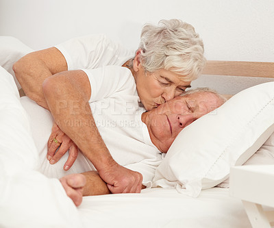 Buy stock photo Senior couple, hug and kiss in bed or relaxing in retirement, love and bonding on weekend. Elderly people, sleeping man and embracing for affection in marriage, romance and morning routine at home