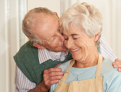 Buy stock photo Senior couple, romance and kiss at home, smile and bonding together in retirement. Elderly people, love and happy in marriage or relationship, weekend and support in commitment or care in kitchen