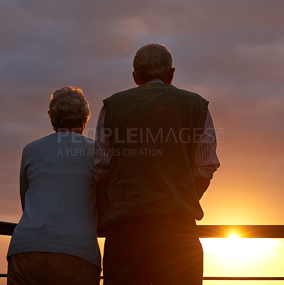Buy stock photo Senior couple, sunset and together on balcony in outdoors, bonding and love on vacation or holiday. Back, elderly people and dusk on terrace and together in nature, security and travel for marriage