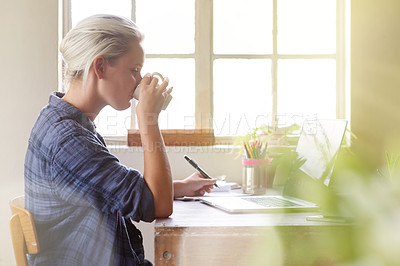 Buy stock photo Shot of a young woman drinking coffee while sitting at her computer at home