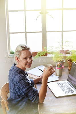 Buy stock photo Portrait of a young woman drinking coffee while working at her computer at home