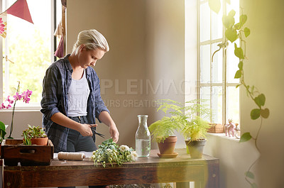 Buy stock photo Shot of a young florist cutting flowers to make up a bouquet