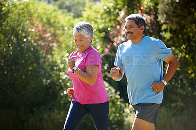 Buy stock photo Shot of a mature couple jogging together on a sunny day