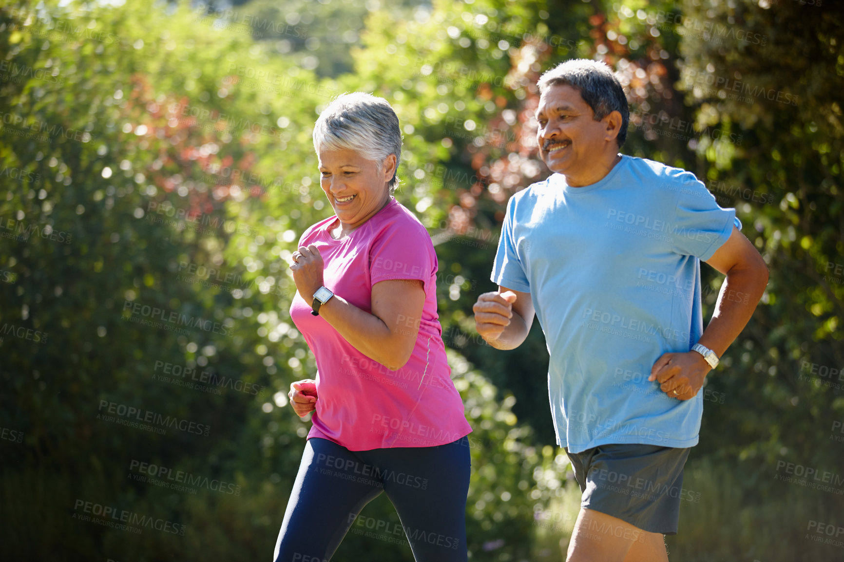 Buy stock photo Shot of a mature couple jogging together on a sunny day