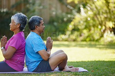 Buy stock photo Shot of a mature couple doing yoga together in their backyard