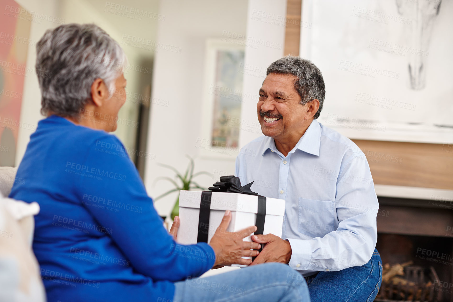 Buy stock photo Shot of a loving senior man surprising his wife with a gift