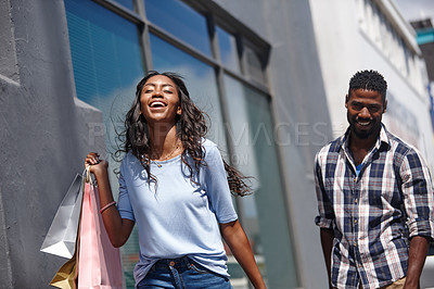Buy stock photo A beautiful woman posing with her shopping bags with a man standing in the background