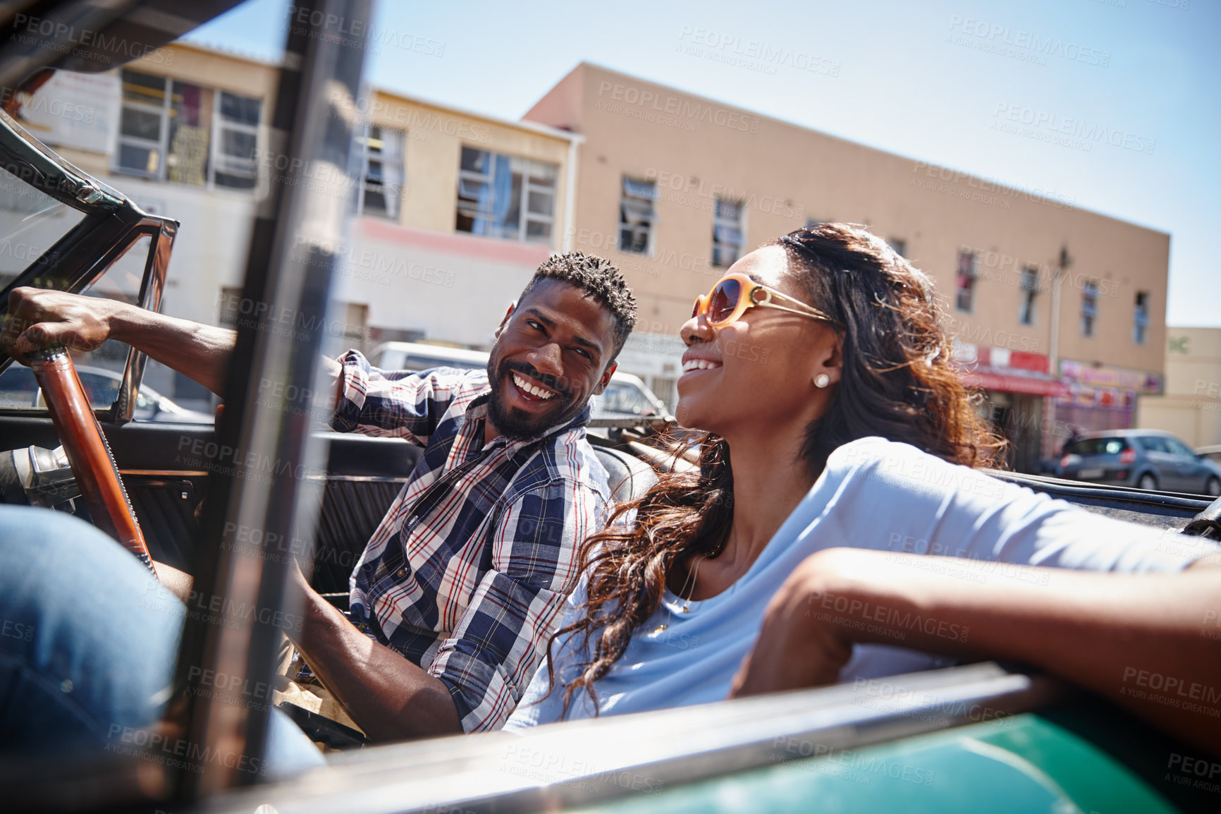 Buy stock photo A happy young couple driving in a convertible on a bright summer's day