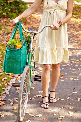 Buy stock photo Cropped shot of a young woman walking home from the grocery store with her bicycle