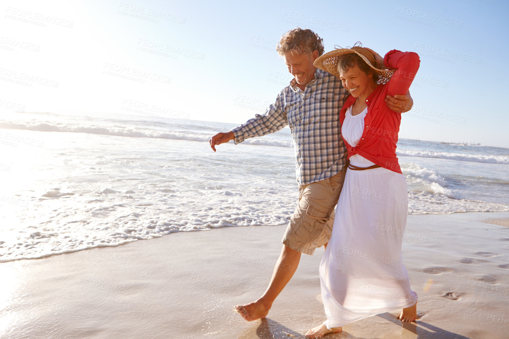 Buy stock photo Shot of a mature couple enjoying a late afternoon walk on the beach