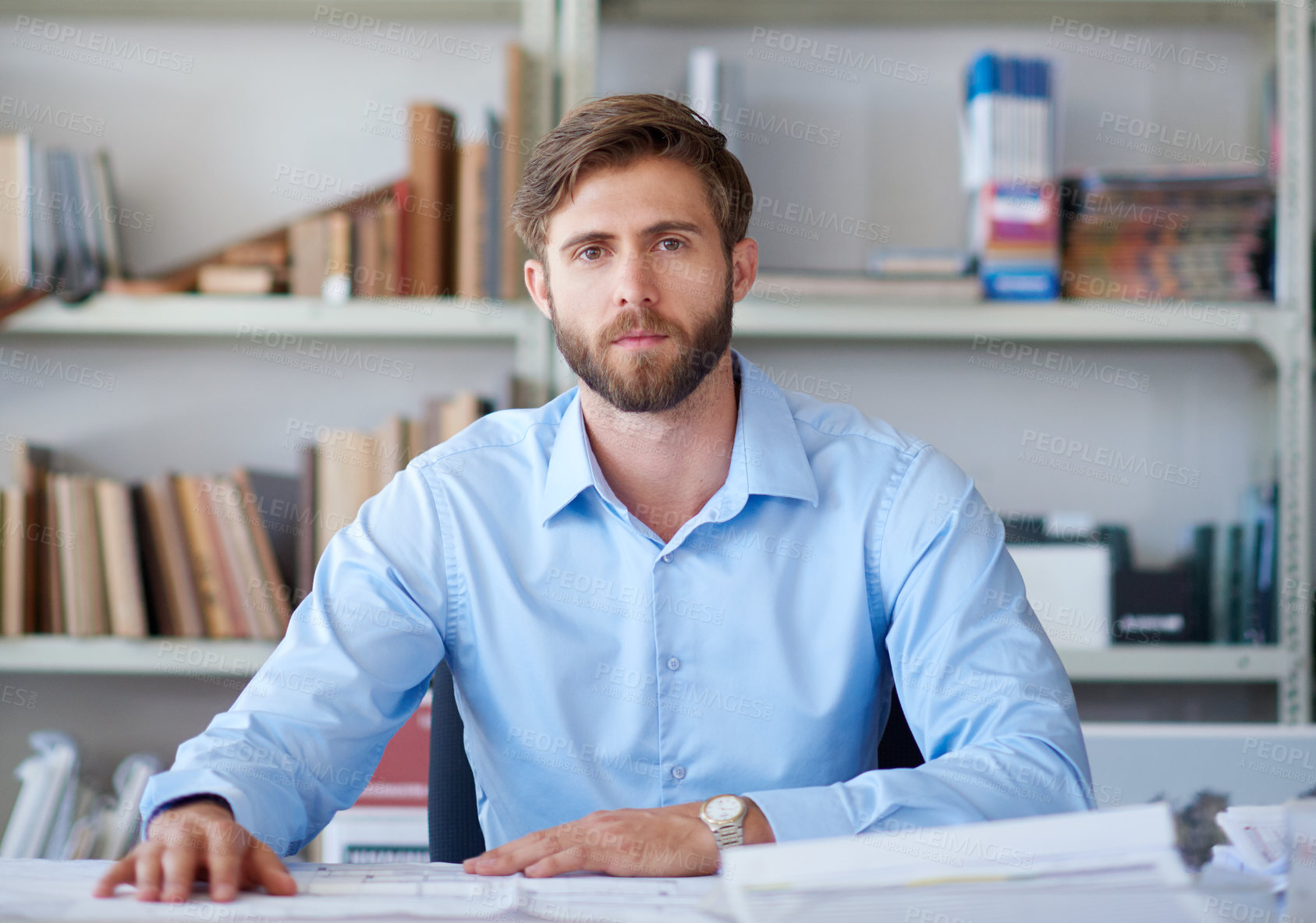 Buy stock photo Portrait of a handsome young architect sitting at his desk with blueprints in front of him