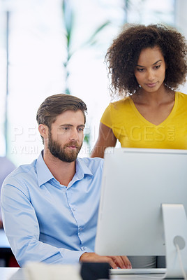 Buy stock photo Cropped shot of two young colleagues working together at a computer