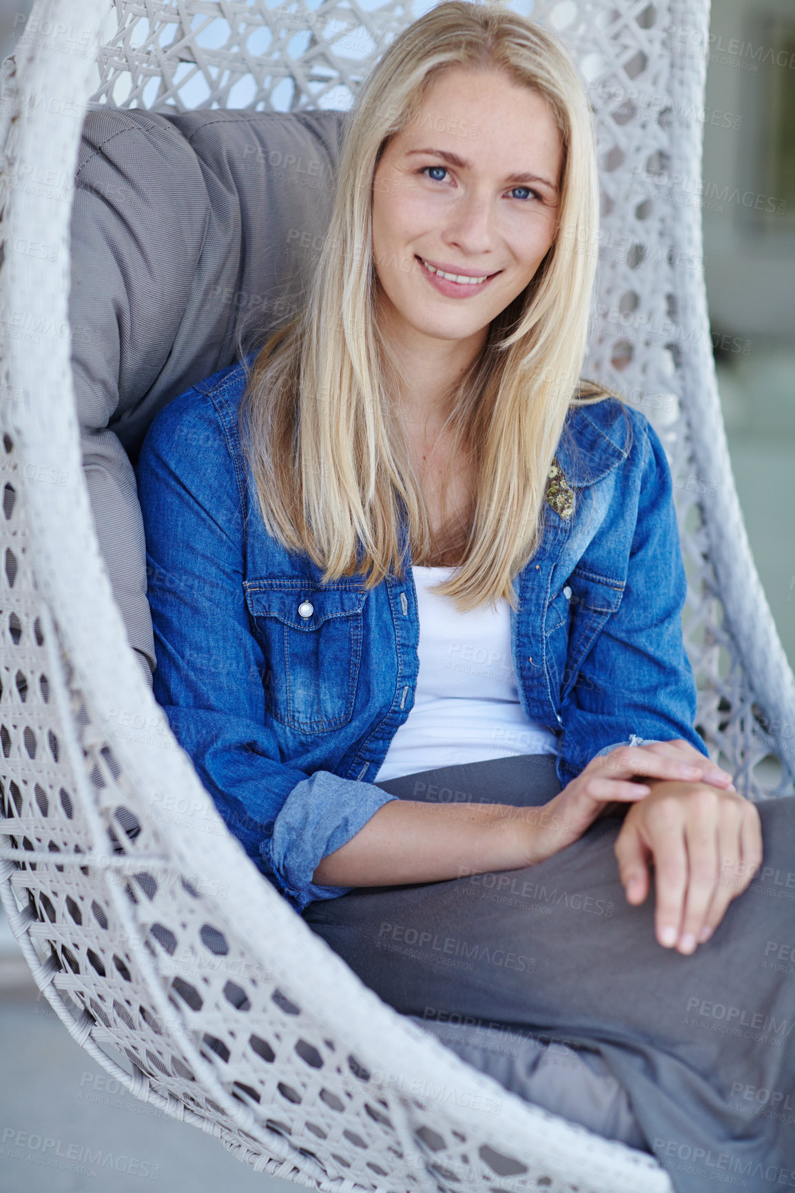 Buy stock photo Shot of an attractive young woman relaxing in a hanging basket chair on her patio