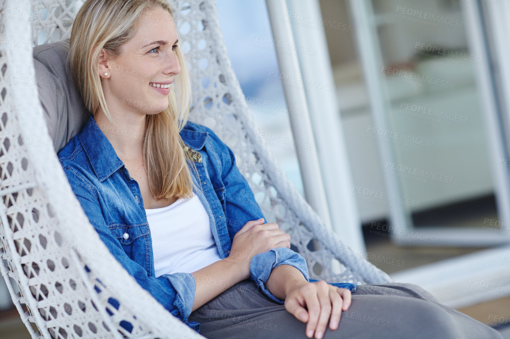 Buy stock photo Shot of an attractive young woman relaxing in a hanging basket chair on her patio