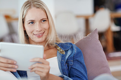 Buy stock photo Shot of an attractive young woman using a tablet while sitting on the sofa