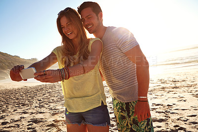 Buy stock photo Cropped shot of an affectionate young couple taking a selfie on the beach