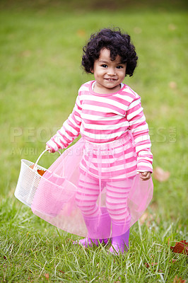 Buy stock photo Portrait, happy child and tutu on grass in park with basket for leaves for autumn. Little girl, pink clothes and curly hair with rain boots for growth, development and changing of season for Easter