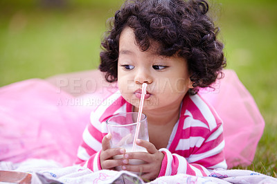 Buy stock photo Girl, child and drinking of milk on grass with straw in pink tutu while lying for picnic. Youth, curly hair and kid with dairy for balanced diet, nutrition and calcium for development of strong bones