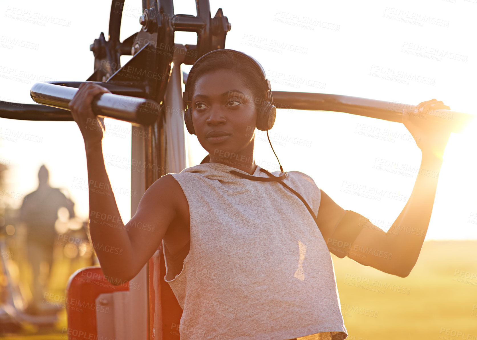 Buy stock photo A young woman using outdoor exercise equipment at the park