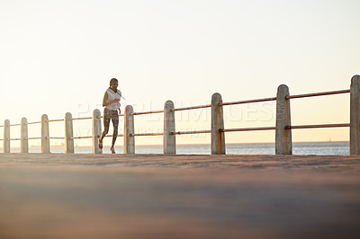 Buy stock photo Black woman, running or fitness at ocean space with music, exercise or cardio training. Girl, headphones or jog on Mozambique promenade for workout, endurance or lose weight with motivational podcast