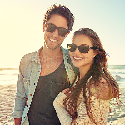 Buy stock photo Couple, ocean and sunglasses with hug, smile or care for fashion, eye protection or vacation in summer. Man, woman and embrace in glasses at beach for sun, happy or love by waves on tropical holiday