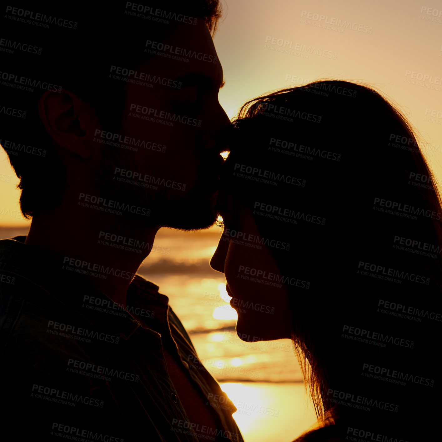 Buy stock photo Couple, love and silhouette embrace on beach at sunset or healing relationship environment, vacation or explore. Happy partnership, hug and shadow at water for forehead kiss for nature, ocean or trip