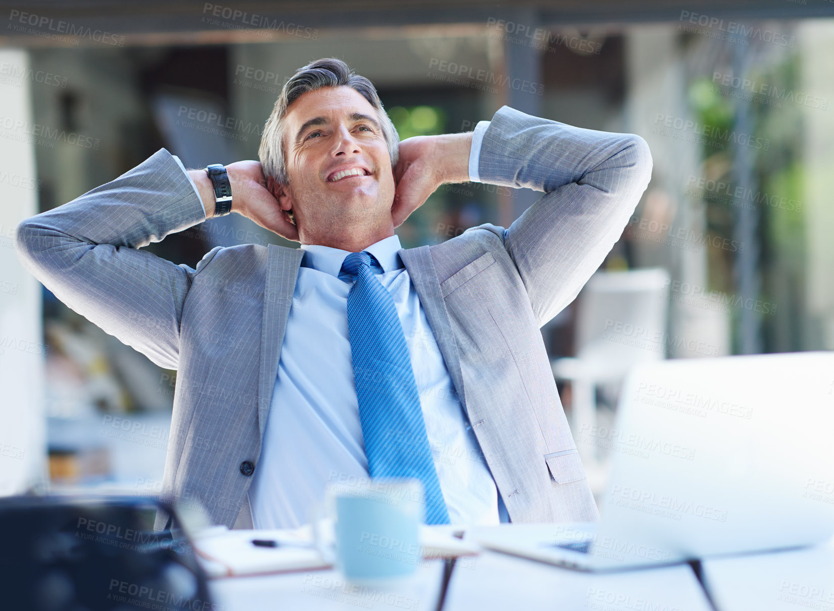 Buy stock photo Shot of a content businessman leaning back in his chair with his hands behind his head