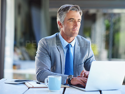 Buy stock photo Shot of a thoughtful-looking mature businessman working on a laptop