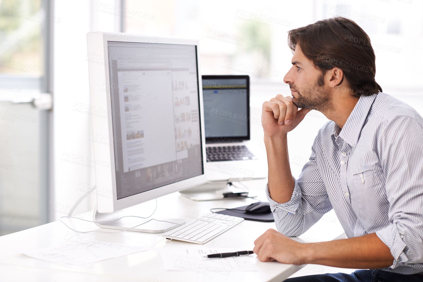 Buy stock photo Shot of a handsome man working on a computer in an office