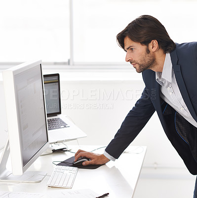 Buy stock photo Shot of a handsome man working on a computer in an office
