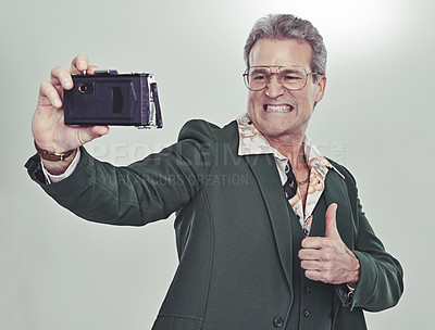 Buy stock photo Senior man, fashion and selfie with thumbs up for good job, winning or photography on a gray studio background. Mature person in retro or vintage style and like emoji or yes sign for photo or picture