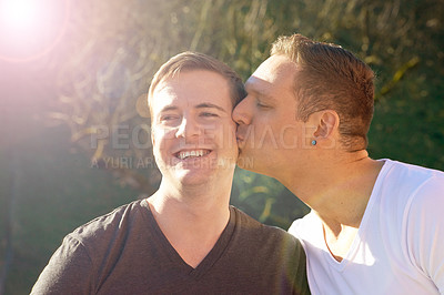 Buy stock photo Gay couple, men and kiss in nature for love, affection and happy married people on honeymoon. Smile, sunshine and flare for partnership and cheek, husband and romance for bonding outdoors for holiday