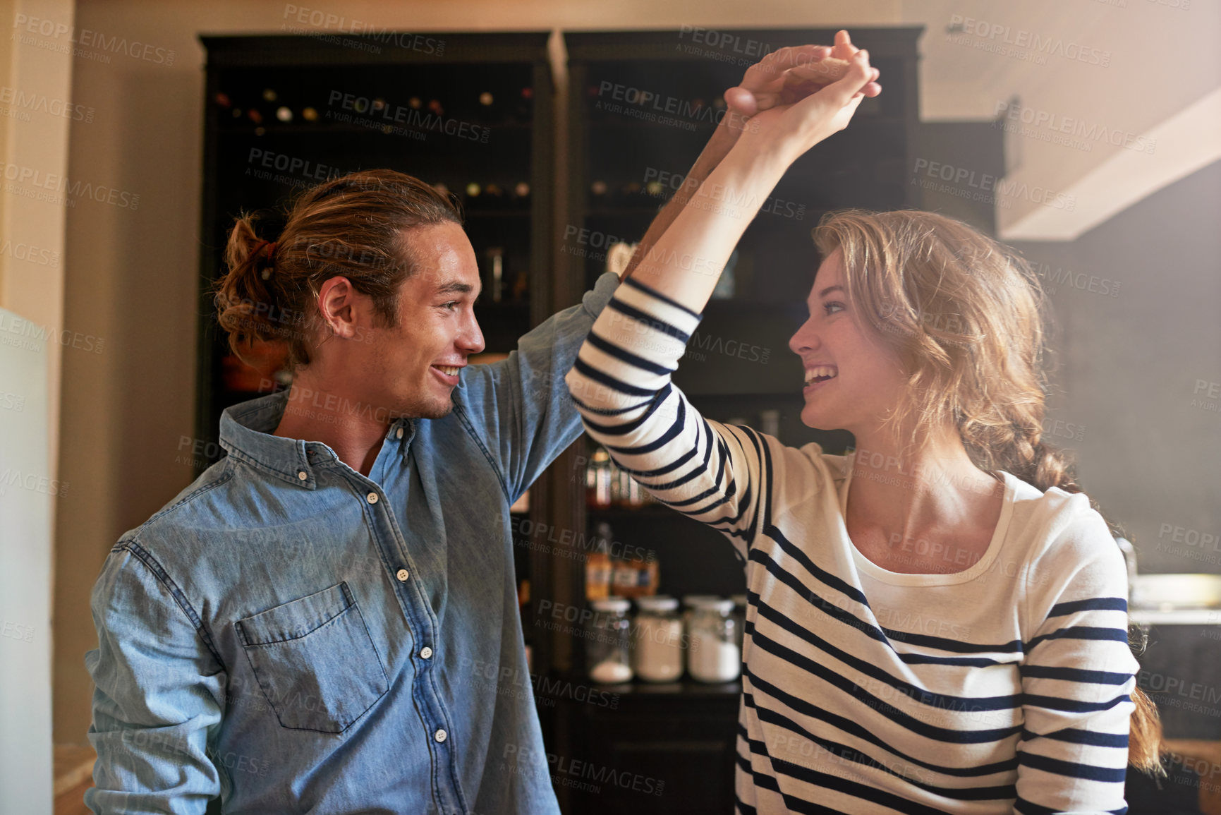Buy stock photo Shot of a young couple dancing in the kitchen