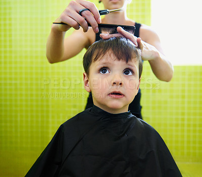 Buy stock photo Child, boy and barber with haircut at salon for grooming, hairstyle or serious with scissors. Hairdresser, person or kid for hair treatment, haircare and hairdressing with comb, confidence or looking