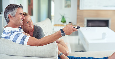 Buy stock photo Shot of mature couple cuddling on the sofa while watching movies at home