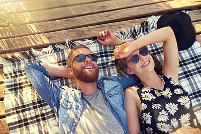 Buy stock photo Shot of an affectionate young couple lying on a blanket outdoors