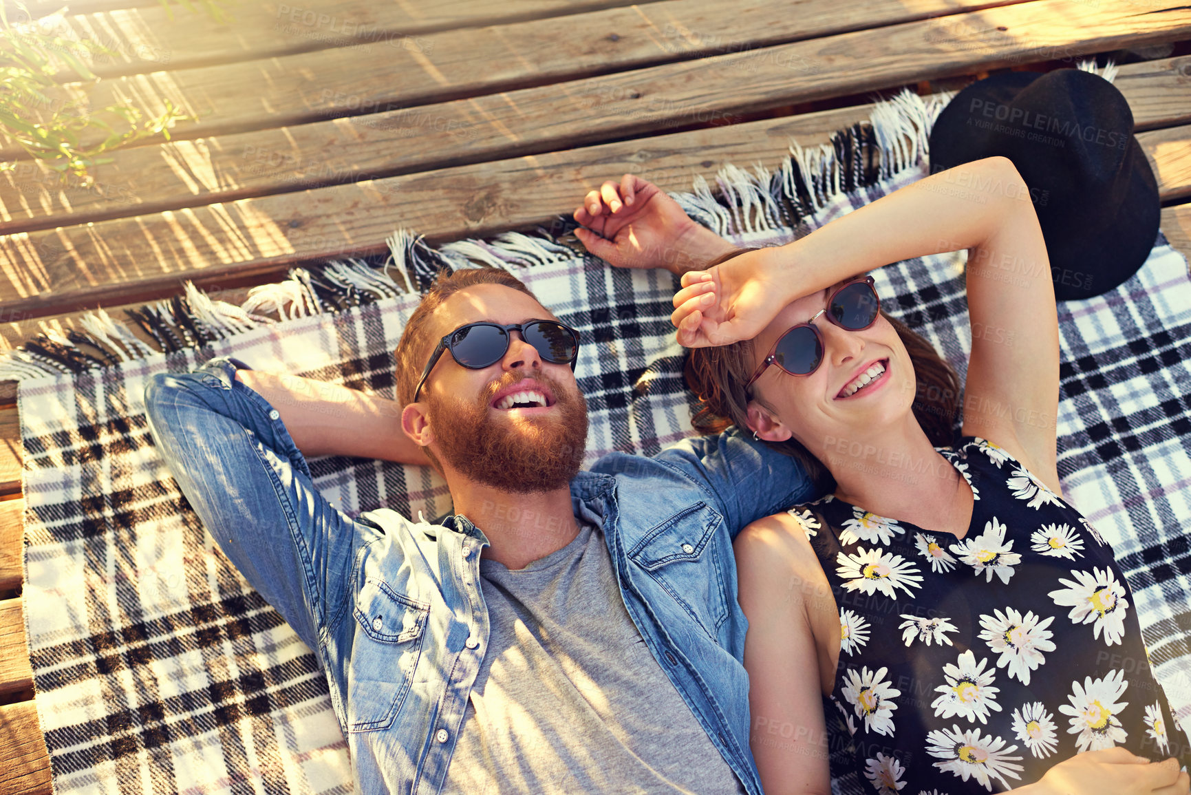 Buy stock photo Shot of an affectionate young couple lying on a blanket outdoors