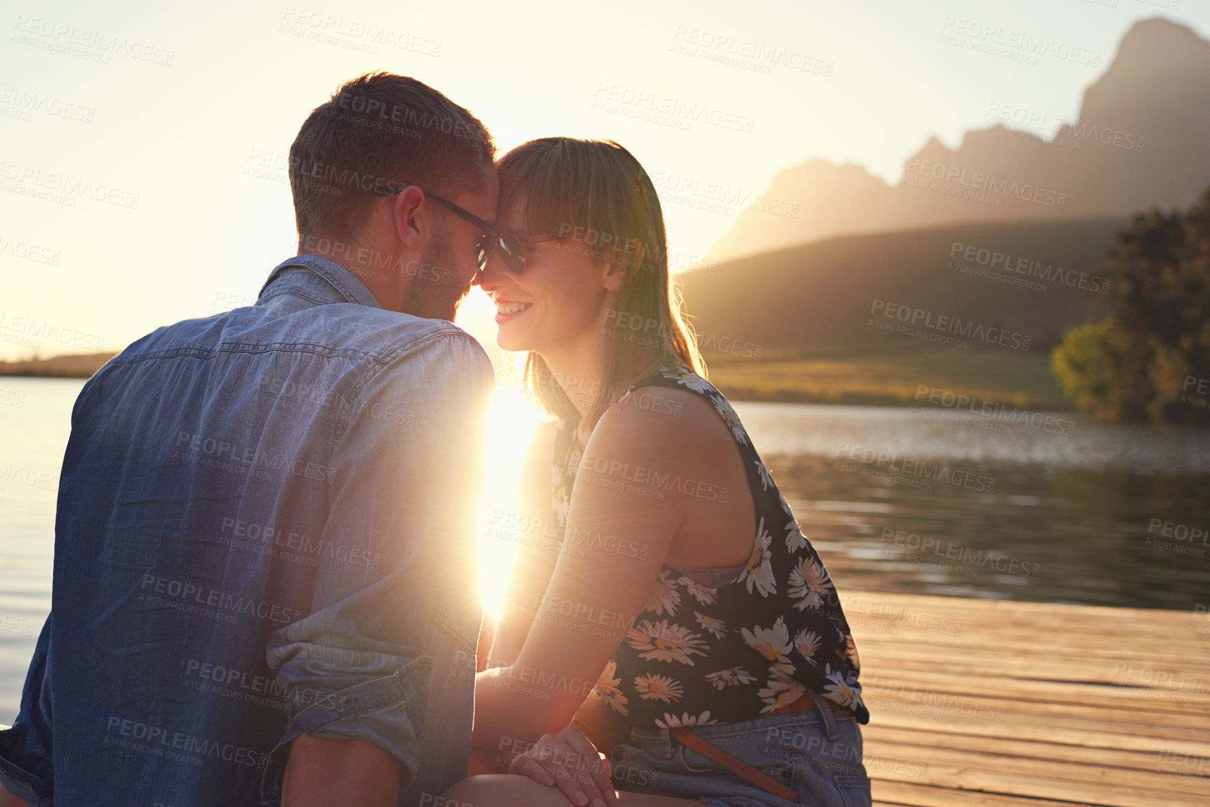 Buy stock photo Couple, sunglasses and sunset on pier by lake with memory, vacation or love in countryside. People, man and woman for forehead touch, water and view in nature with bonding, smile or holiday in Italy