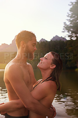 Buy stock photo Shot of an affectionate young couple hugging while swimming in a lake