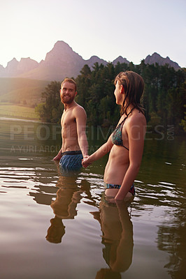 Buy stock photo Shot of an affectionate young couple swimming in the lake