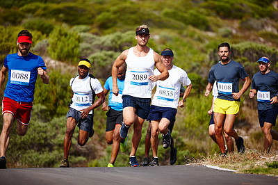 Buy stock photo Shot of a group of young men running a marathon