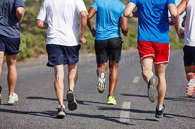 Buy stock photo Cropped rearview shot of a group of men running a road race