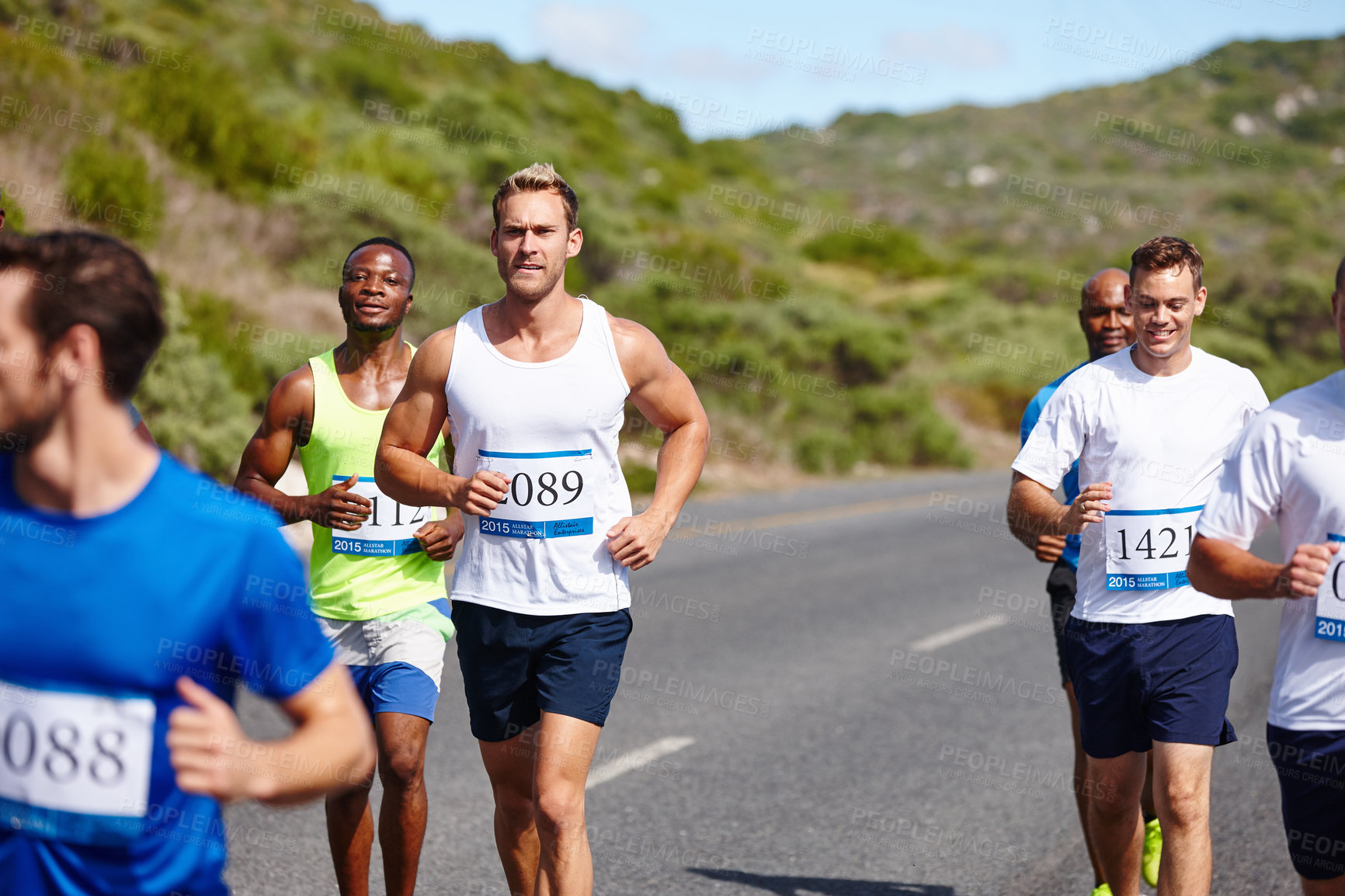 Buy stock photo Shot of a group of young men running a marathon