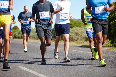 Buy stock photo Cropped shot of a group of men running a marathon