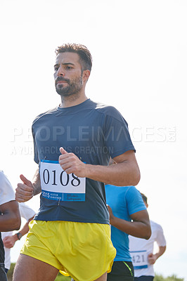 Buy stock photo Shot of a young man running a marathon with other runners in the background